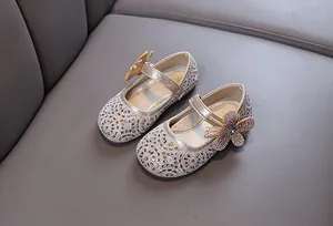 Close-up of golden sparkly girl's princess shoes with rhinestone butterfly