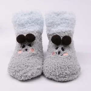 Detailed view of cute plush baby floor socks with cartoon face and pom-poms