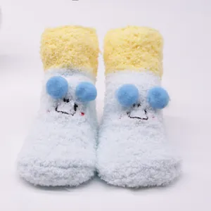 Close-up of cute light blue plush baby socks featuring a cartoon face and non-slip floor grip