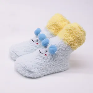 Detail view of cute plush cartoon baby socks with blue pom-poms and yellow trim