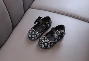 Macro view of girls' black rhinestone Mary Jane shoes with elegant butterfly bow