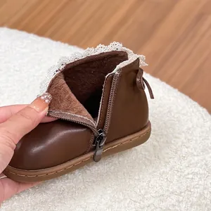 Primer plano de botas de cuero marrón para niña con forro polar cálido y encaje.