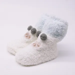 Detail view of soft white and blue plush baby floor socks with cute embroidered cartoon face