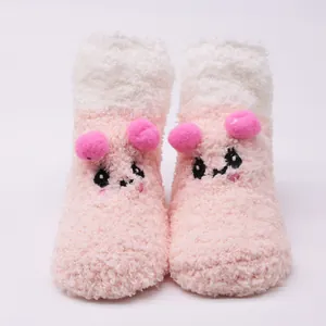 Front detail of cute plush pink and white baby socks with cartoon animal face and pom-poms