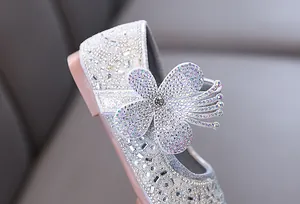 Close-up detail of girls' silver princess shoes with sparkling rhinestone flower decor