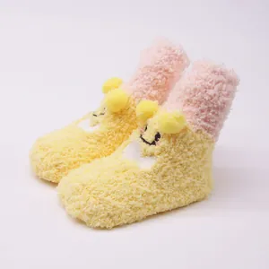 Close-up of cute plush baby floor socks with cartoon smiley face and pom-poms