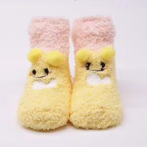 Cute yellow plush baby floor socks with cartoon face and soft pom-poms for winter warmth