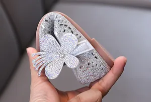 Close-up of flexible silver princess shoe with rhinestone butterfly detail