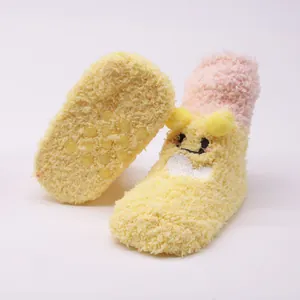 Macro view of fuzzy baby socks showing cartoon face detail and anti-slip sole dots