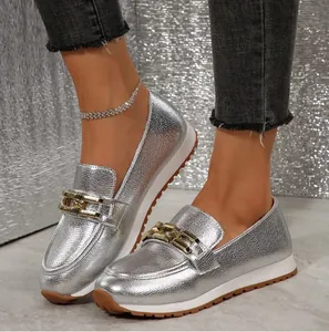 Detaillierte Nahaufnahme silberner Metallic-Loafer mit goldener Kette und Gummisohle