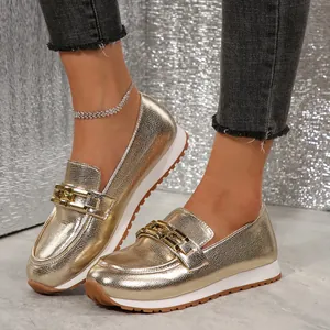 Detailansicht goldener Slipper mit Schlangenmuster und eleganter Metallkettenschnalle