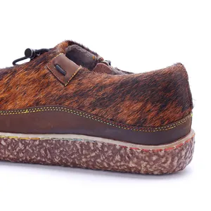 Macro view of handmade leather shoe showing pony hair texture and colorful stitching