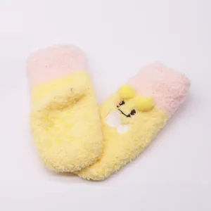 Detail view of yellow cartoon plush baby socks with anti-slip dots on white background.