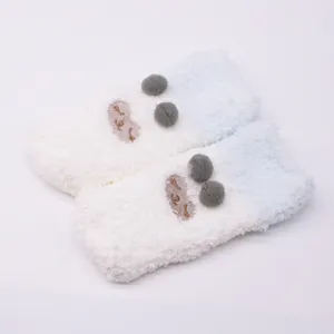 Close-up detail of white and blue fuzzy baby socks with cute pom-pom and embroidery details