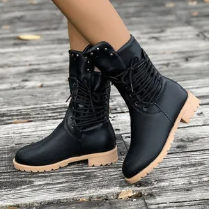 Close-up of black mid-calf studded riding boots with lace-up front and tan lug sole