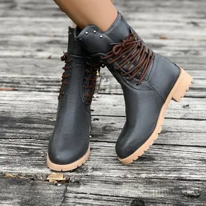 Detailed view of dark grey mid-calf Martin boots with brown laces and studs