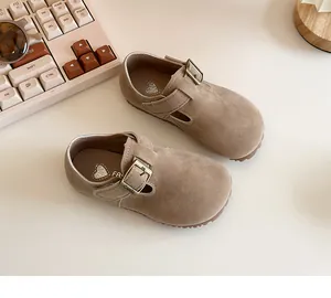 Macro detail of classic tan suede children shoes featuring vintage metal buckle strap