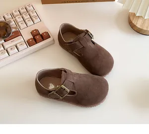 Detailed macro view of brown suede children's shoes featuring vintage bronze metal buckles.