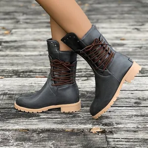 Grey mid-calf lace-up combat boots with studs and back zipper on wooden floor