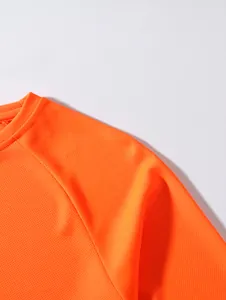 Close-up of breathable orange mesh fabric and shoulder stitching on a men's t-shirt