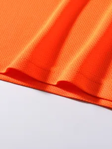 Close-up of breathable orange mesh fabric and double-stitched hem on long-sleeved shirt