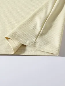 Macro detail of breathable mesh fabric and hem stitching on men's long sleeve base layer.