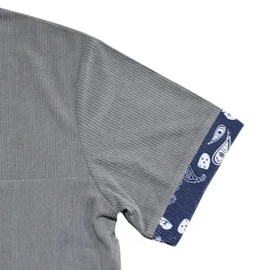 Detail view of a gray corduroy short sleeve shirt featuring paisley patterned cuffs.