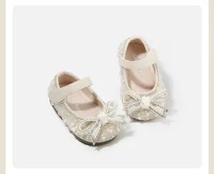Detailed top view of cream baby girl princess shoes with pearls and a rhinestone bow.