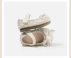 Detailed macro view of cream baby girls' princess shoes with pearls, rhinestones, and bow