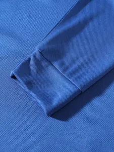 Detailed macro view of the ribbed cuff and breathable mesh fabric on blue long sleeve top