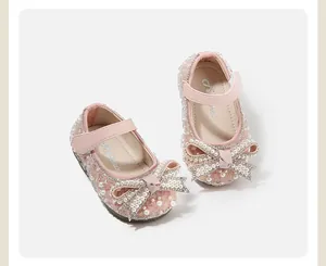 Close-up detail showing pearls and rhinestone bow on pink baby girl princess shoes