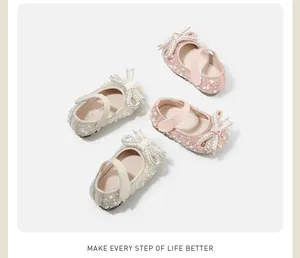 Detailed view of baby girl princess shoes in pink and beige with pearls and bows.