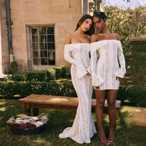 Detail of elegant off-the-shoulder white lace dresses with long bell sleeves in a garden