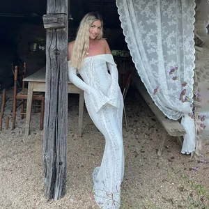 Elegant off-shoulder white lace maxi dress with long sleeves in a rustic outdoor setting