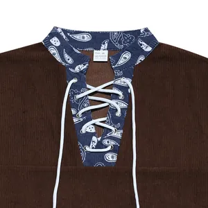 Detail of brown corduroy Henley shirt with blue paisley pattern and white lace-up neck