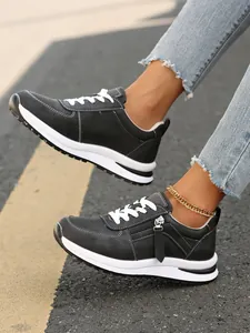Άνετα μαύρα γυναικεία φλατ sneakers με στρογγυλή μύτη, κορδόνια και πλαϊνό φερμουάρ.