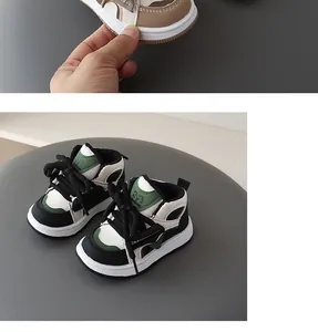 Close-up detail of children's high-top sneakers with thick black laces and green accents