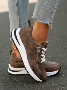Κοντινό πλάνο καφέ distressed sneakers με λευκά κορδόνια και λεπτομέρεια φερμουάρ