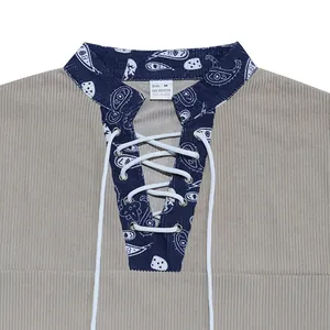 Close-up of corduroy Henley shirt featuring paisley trim and lace-up neckline detail.