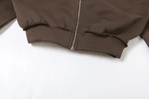 Gros plan du zip métallique et de l'ourlet côtelé d'une veste à capuche marron à fermeture