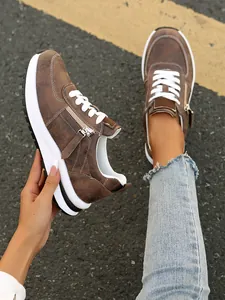 Λεπτομερής άποψη από καφέ γυναικεία sneakers με πλαϊνό φερμουάρ και λευκά κορδόνια.