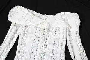 Detail of white lace off-the-shoulder dress featuring hollow patterns and drawstring