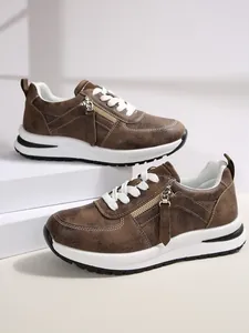 Λεπτομέρεια καφέ sneakers με χρυσό πλαϊνό φερμουάρ και χοντρή λευκή σόλα για άνεση