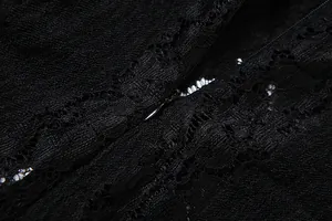 Macro detail of the invisible zipper and delicate floral lace fabric of the black dress