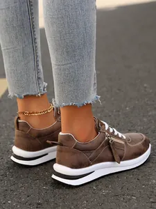 Λεπτομερής άποψη των γυναικείων καφέ sneakers με πλατφόρμα, φερμουάρ και λευκά κορδόνια