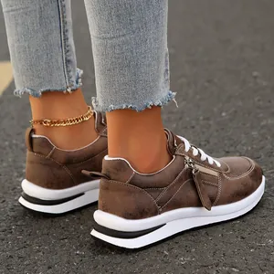 Κοντινό πλάνο γυναικείων καφέ sneakers με πλατφόρμα, πλαϊνό φερμουάρ και λευκή χοντρή σόλα.