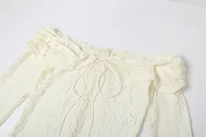 Close-up of off-the-shoulder lace dress with delicate hollow-out details and bow tie