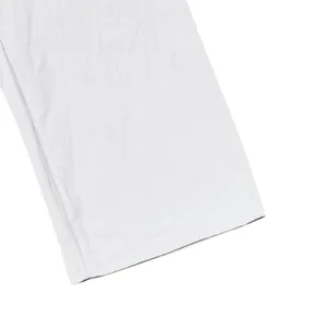 Close-up detail of white breathable linen trousers hem showing fabric texture and stitching