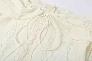 Close-up of white lace dress showing drawstring detail and delicate hollow pattern.
