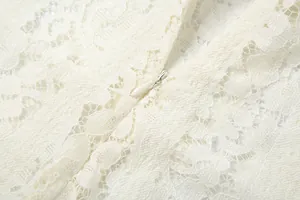 Close-up macro shot of delicate white floral lace texture and hidden zipper detail.
